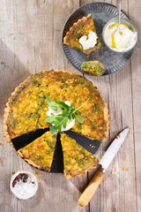 Quiche with arugula, onion, spinach, mozzarella, feta and sauce on rustic background, top view. Homemade, traditional french quiche pie.