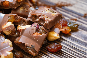 Close up of milk chocolate with hazelnuts and raisins. Milk chocolate in pieces.