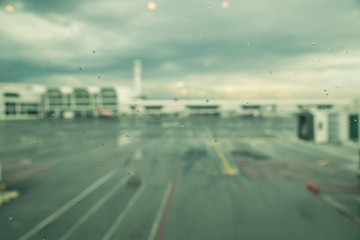 Rain drops on window of airport, monsoon season in South East Asia. Blurred aircraft and terminal. Transportation weather concept.