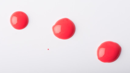Three red nail polish drops on a white background.
