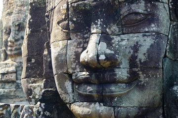Stone faces in Bayon, Angkor Thom temple, selective focus sunset light. Buddhism meditation...
