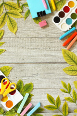 Back to school concept. Flatlay background. Table with autumn leaves and different school supplies, stationery, pencils. Free space for your text.