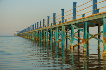 long colorful bridge to sea horizon line at summer sunset