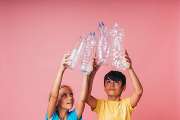 Two little boys holding a plastic bottles for recycling