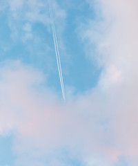 Trail from the plane in the sky at sunset