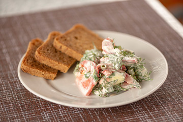 Green vegetables salad. Tomatoes, cucumbers, onions, parsley, fennel, sour cream, bread, sandwiches. A table in summer cafe.