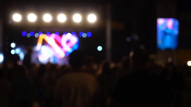 Concert on the stage. Crowd of people and musicians on the scene. Out of focus.