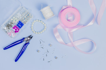 Equipment for making the hand made earrings with pink ribbon on blue background