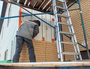 Worker installs plastic panels with bricks