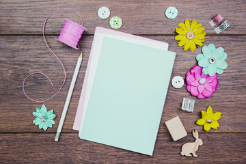 White pencils; buttons; colorful flowers and pink spool on wooden table