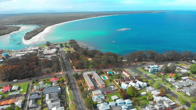 Aerial dolly in view over Huskisson town and Jervis Bay by the ocean in Australia.