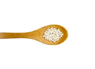 Wood spoon with small white round homeopathy pills isolated on white background, copy space.