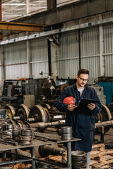 Fototapeta na wymiar Manual worker looking at clipboard at metal manufacturing plant. Production of steel train wheels.