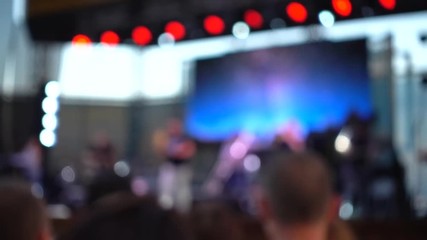 Concert on the stage. Crowd of people and musicians on the scene. Out of focus.