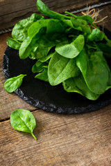 Fresh salad spinach leaves on the wooden kitchen table. Free space for your text.