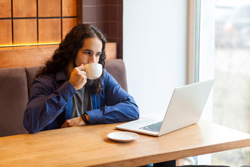Portrait of satisfied handsome intelligence young adult man freelancer in casual style sitting in...