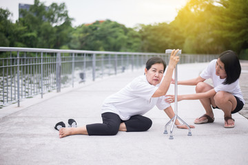 Senior asian woman with faint sitting on floor after falling down,female take care and support