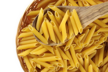 Penne rigate pasta in wooden food basket with wooden spoon isolated on white background, top view