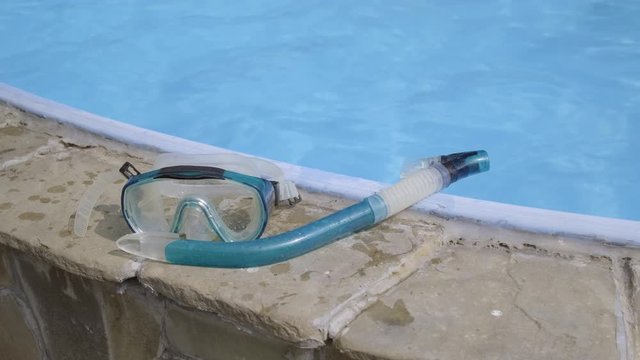 diving mask and snorkel near swimming pool with blue water. concept of summer recreation and entertainment.