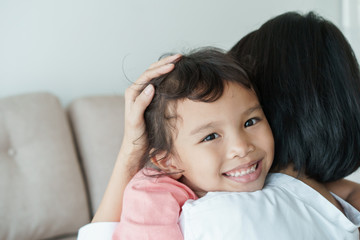 Family Asian with mother and daughter hug with love while sitting in the living room at home. Close-up on the face little girl