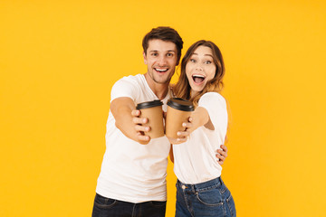 Portrait of young couple man and woman smiling at camera while standing together and drinking...