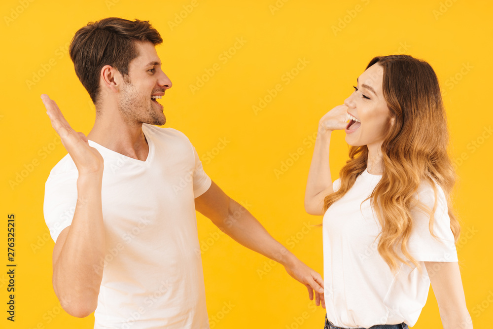 Wall mural Portrait of joyful couple man and woman in basic t-shirts rejoicing while giving high five together