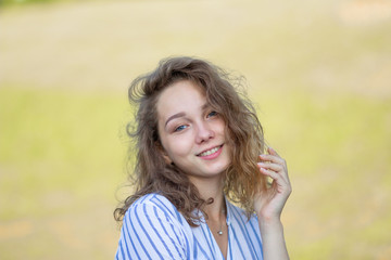 Portrait of beautiful and smiling young woman looking at camera in summer park
