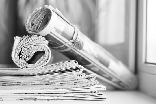 Pile of fresh morning newspapers on the table at office. Latest financial and business news in daily paper. Pages with information (headlines, articles, photos, text). Folded and stacked journals