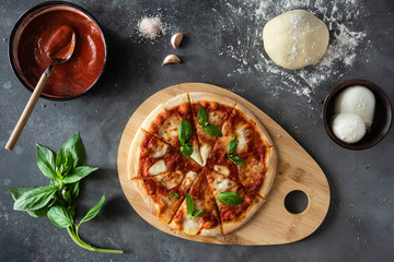 Top view of Pizza Margherita on black stone background. Classic Italian Pizza Margarita with Tomato...