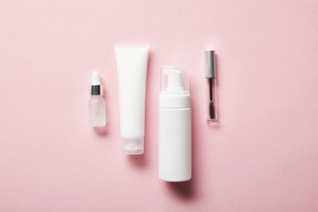 cream tube with hand cream, cosmetic dispenser, empty jar and mascara bottle on pink - obrazy, fototapety, plakaty