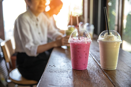 Many types of milk shake in plastic cup with plastic straw put on wood  table , soft sunlight through branch to table in coffee shop. - Stock Image  - Everypixel