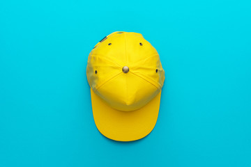 Top view of the yellow baseball cap on turquoise blue background. Flat lay image of baseball cap...