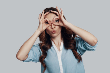 So much fun! Beautiful young woman puckering and gesturing while standing against grey background