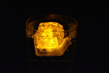 Very beautiful and stunning images of drinks with glowing ice cubes.  Bright colors with bubbles in a glass of champagne.  Promotional image of a relaxing, dear life and a tasty sparkling drink.