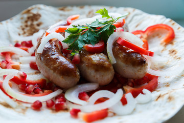 Fried pork sausages on pita bread with ketchup and Armenian appetizer Aivar with vegetables. Lavash, red bell pepper, onions, sausages. Oktoberfest food, the concept of the pub