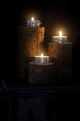 three candles lit in wooden candlesticks