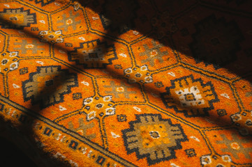 Image of a red ornamental carpet with lights nad shadows of a window on it.