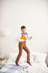 joyful little boy jumps on the bed with a globe in his hands and enjoys the beginning of the school year. happy child is about to go to school. back to school