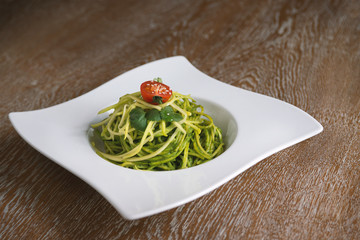 green spinach spaghetti with cheese and tomato on wooden table