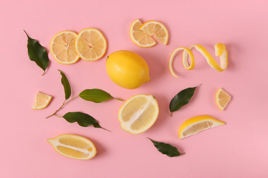 lemons and green leaves on a colored background top view. - Powered by Adobe