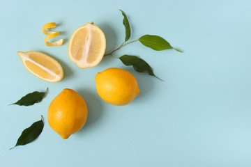 lemons and green leaves on a colored background top view.