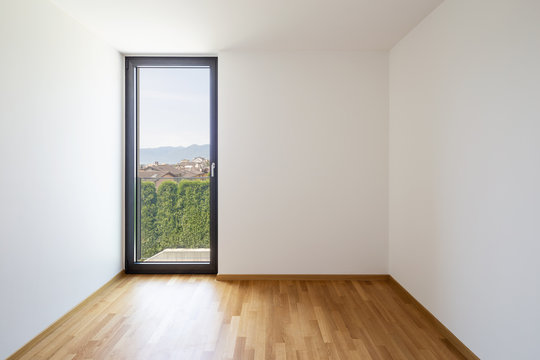 Empty white room with light parquet and window overlooking Lake Maggiore
