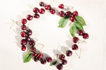 Circle made of fresh ripe cherries on the white surface.Empty space for text