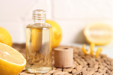 Bottle of essential oil of lemon and lemons on a light background