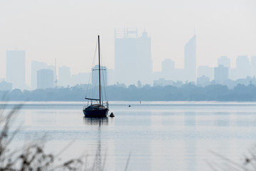 Sailboats in the Swan River with the silhouette outline of Perth, Western Australia, in the background.