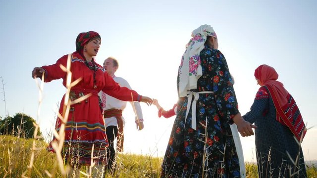 People in traditional russian clothes walking in a circle, sing and having fun