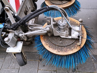 Blaue Reinigungsbürsten einer Kehrmaschine der Stadtreinigung auf den grauen Pflastersteinen des...