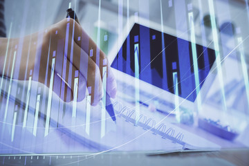 Financial forex graph drawn over hands taking notes background. Concept of research. Multi exposure