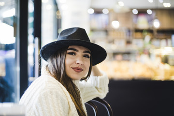 Beautiful smiling young woman wearing black hat on head