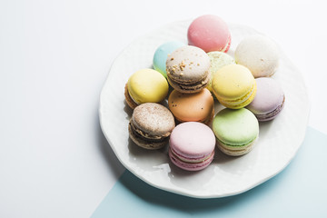 Colorful macaroons on white plate against white background